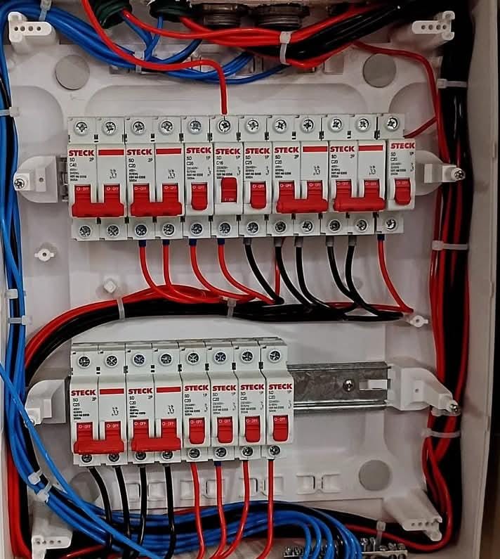 quadro de distribuição elétrica branco com disjuntores Steck de alavancas vermelhas e fiações vermelhas, azuis